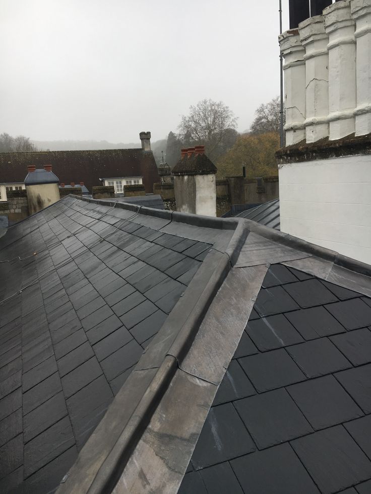 Pitched slate roof with chimneys on a foggy day