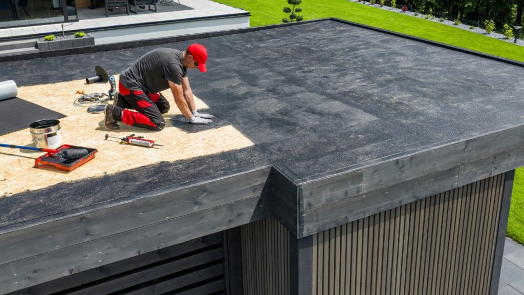 A worker installing roofing material on a flat roof